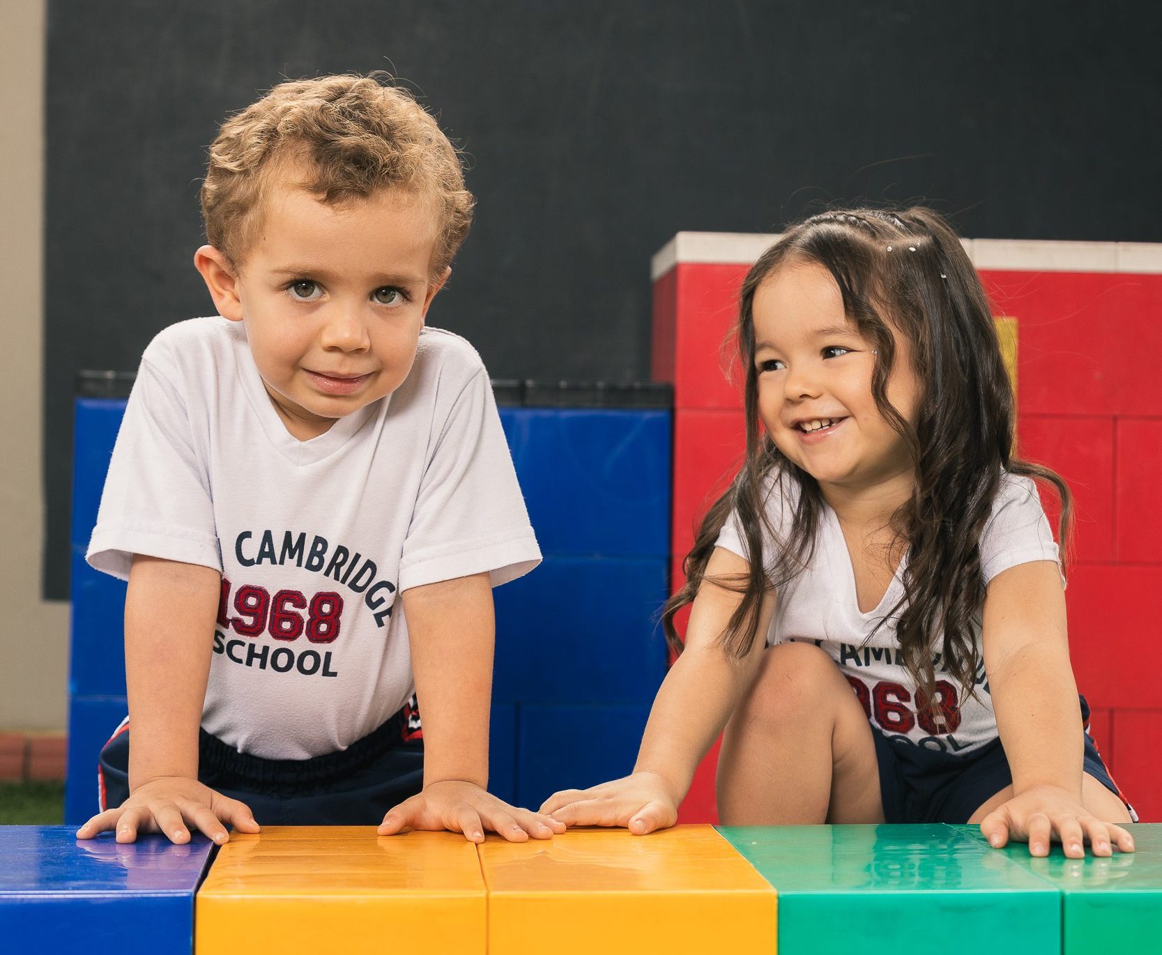 Estudiantes que se sostienen de unas piezas de lego de tamaño grande y de varios colores