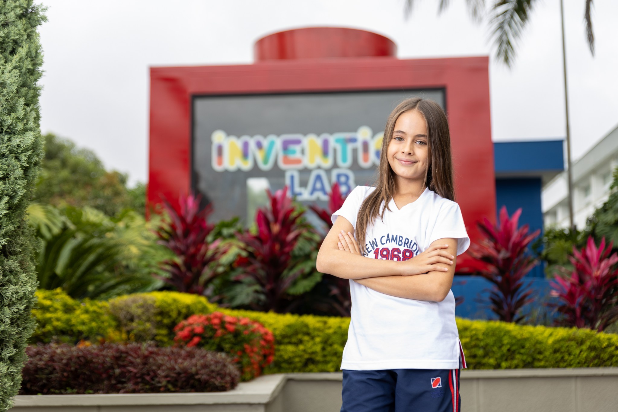 Estudiante de brazos cruzados, con el uniforme de diario. Detrás de ella se ve el Invention Lab de la sede Cañaveral