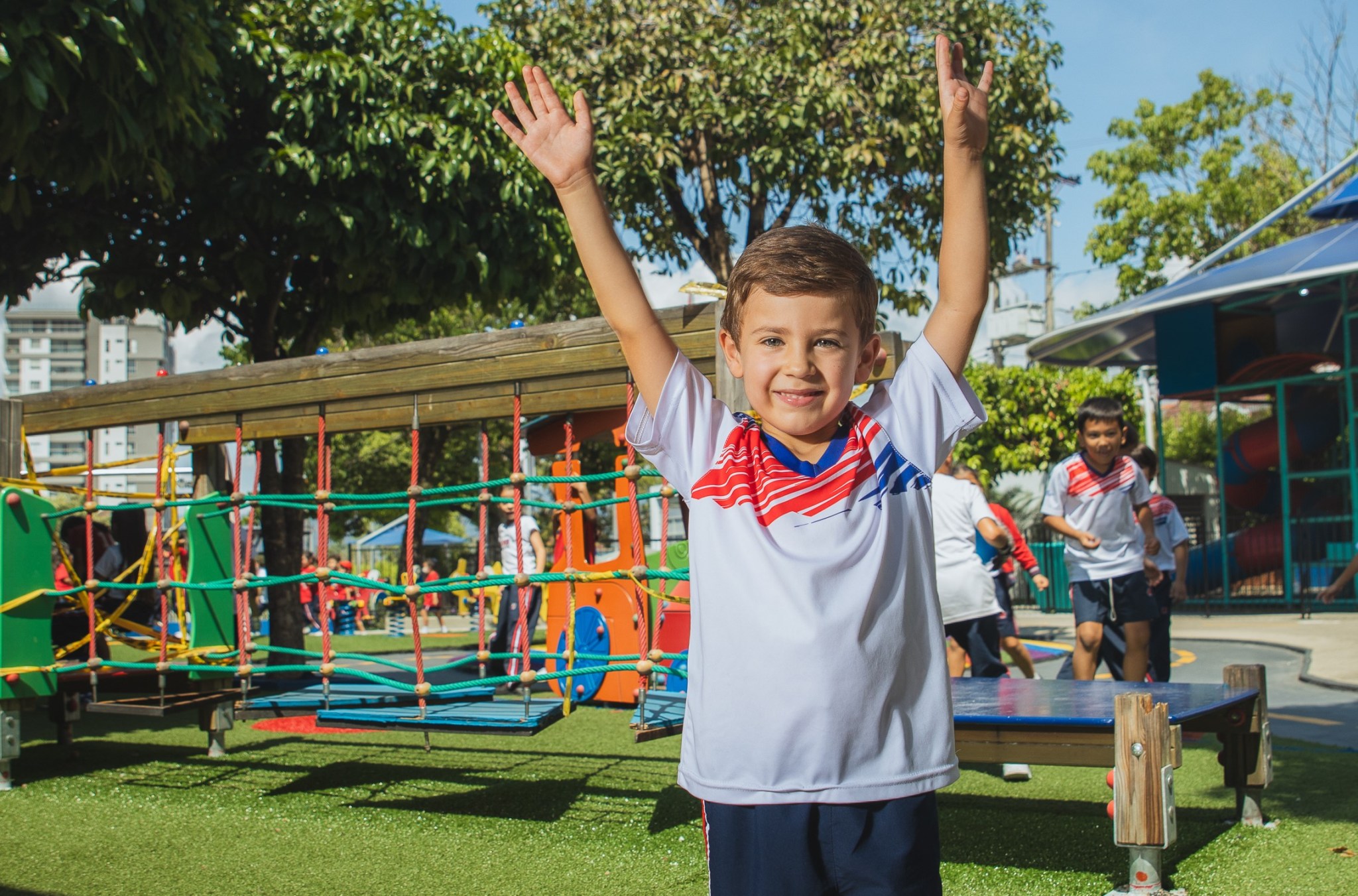 Niño sonriente mirando a la cámara y alzando los brazos