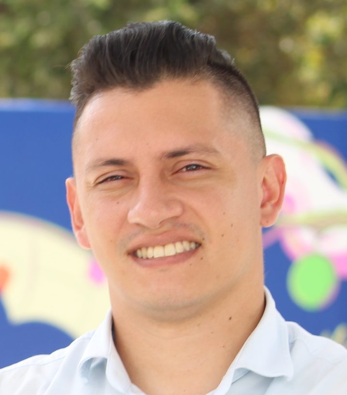 Hombre de camisa blanca, que mira a la cámara, sonriendo