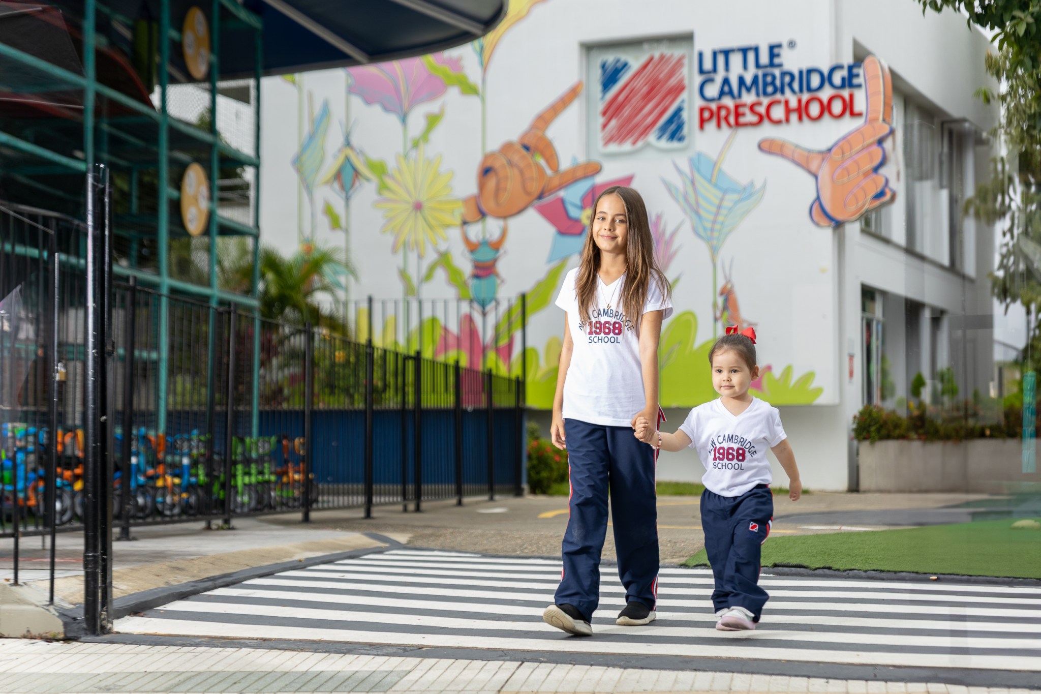 Dos estudiantes van de la mano caminando, mientras salen de Little Cambridge Cañaveral