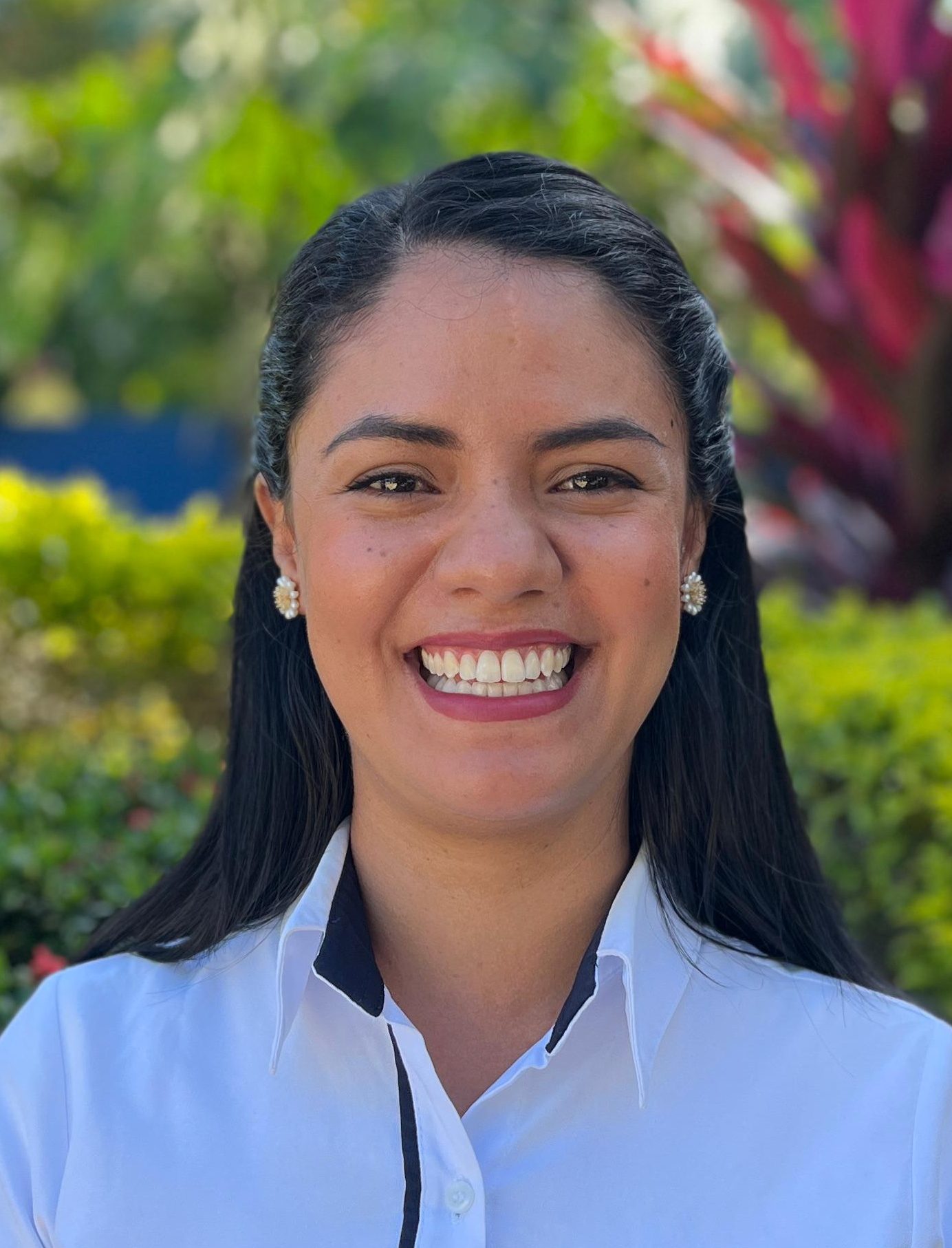Coordinadora de transporte en primer plano, sonriendo a la cámara, con camisa blanca