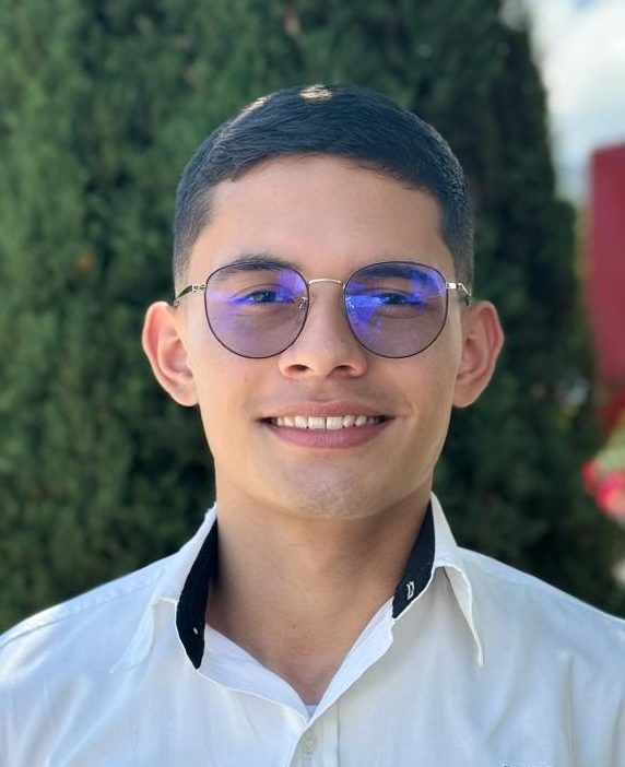 Asesor comercial de la tienda Escool, en primer plano, con camisa blanca