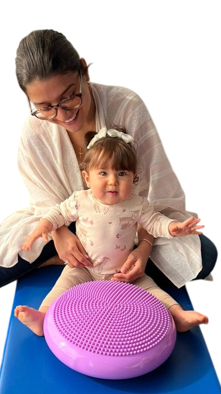 Mamá con su hija en clase de Little Skills, sobre una colchoneta azul. Delante de la bebé hay un cojín lila con textura en la parte superior