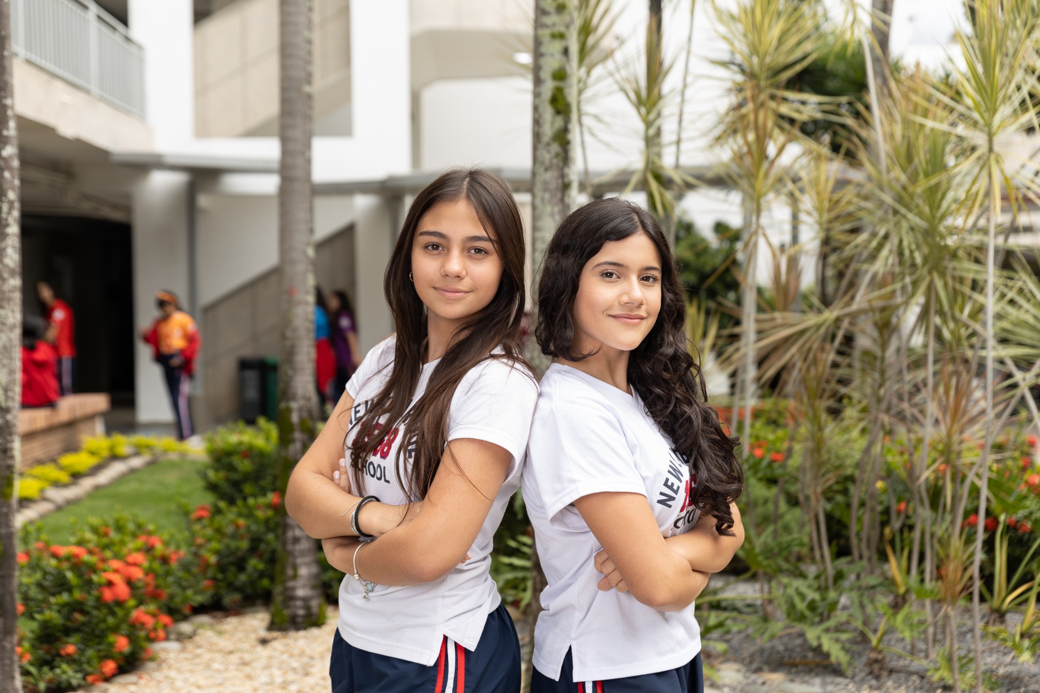 Estudiantes de Lower Secondary con sus espaldas juntas y brazos cruzados, en plano medio